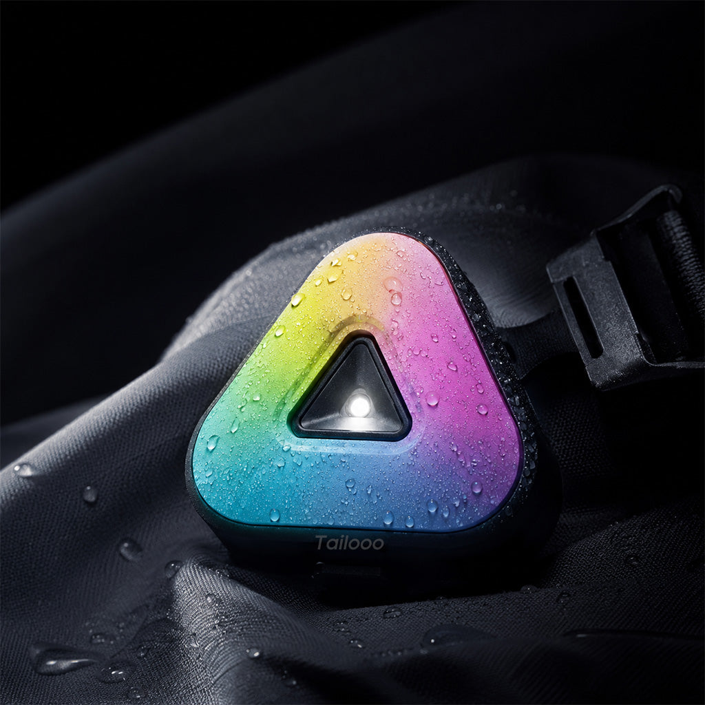 Close-up of Tailooo triangle RGB dog collar light covered in water droplets on a dark wet surface, demonstrating waterproof performance.
