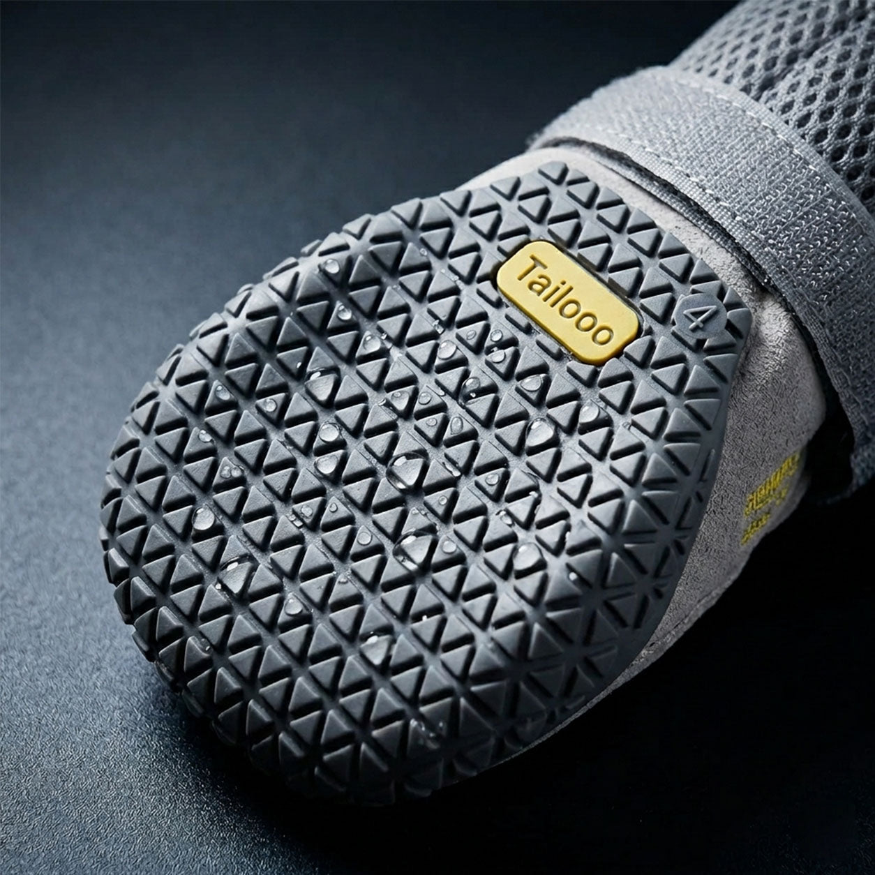 Bottom view of a Tailooo dog boot showing the dense triangular tread pattern on the anti-slip wear-resistant rubber sole with water droplets.