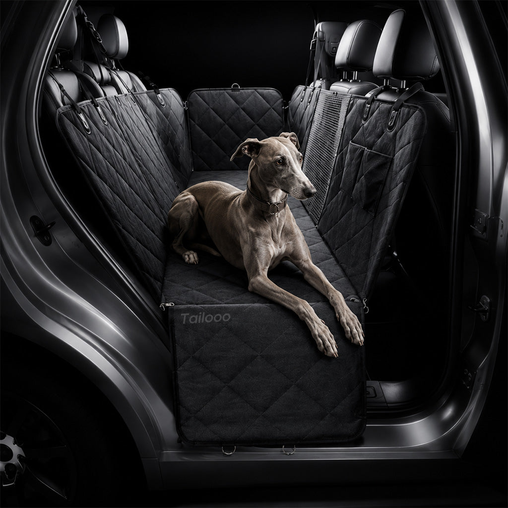 A greyhound relaxing on a black quilted dog car seat cover inside an SUV rear seat, showing full coverage and comfortable fit.