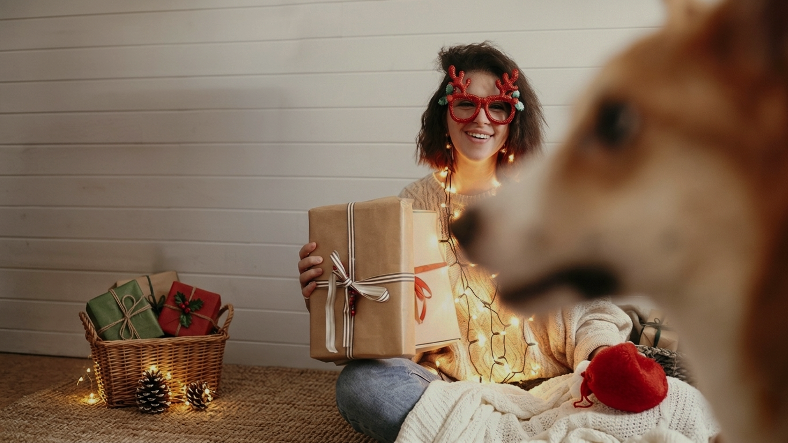 Woman opening Christmas gifts with her dog, creating a warm and festive holiday moment with pet-friendly presents.