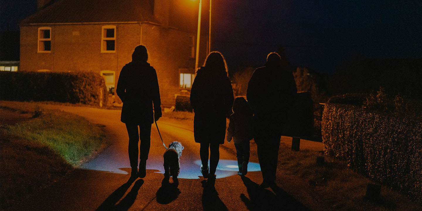 Family walking a dog at night with a bright LED dog light, ensuring pet visibility and safety during evening walks.