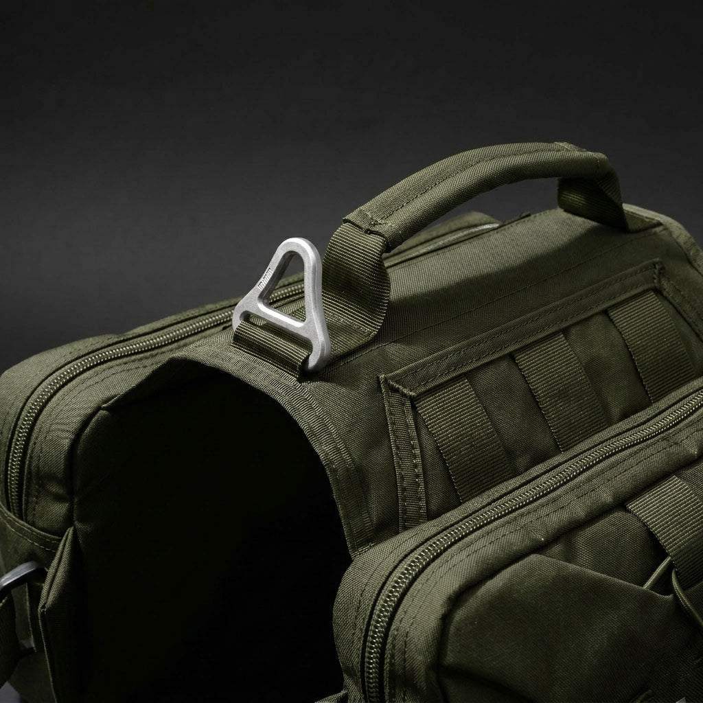 Close-up of Tailooo dog hiking pack top handle and aluminium alloy triangular D-ring on dark background, showing durable hardware and control handle design.