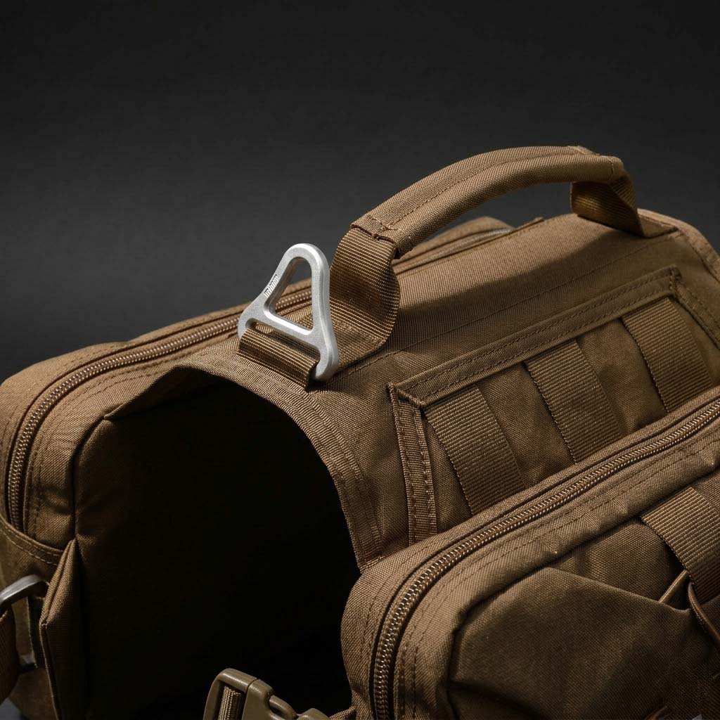 Close-up of Tailooo dog hiking pack top handle and aluminium alloy triangular D-ring on dark background, showing durable hardware and control handle design.