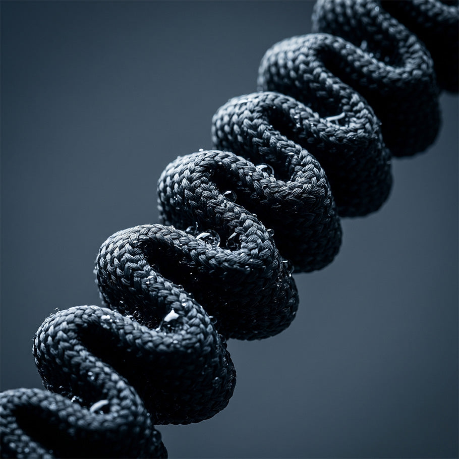 Macro shot of a coiled black bungee cord on a dog leash, highlighting the elastic shock-absorbing construction for large dogs.