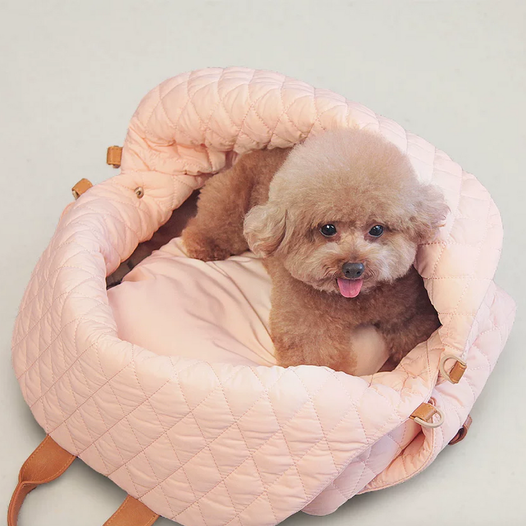 Small dog relaxing in a pink dog safety seat car during a road trip, offering a comfortable and secure view.