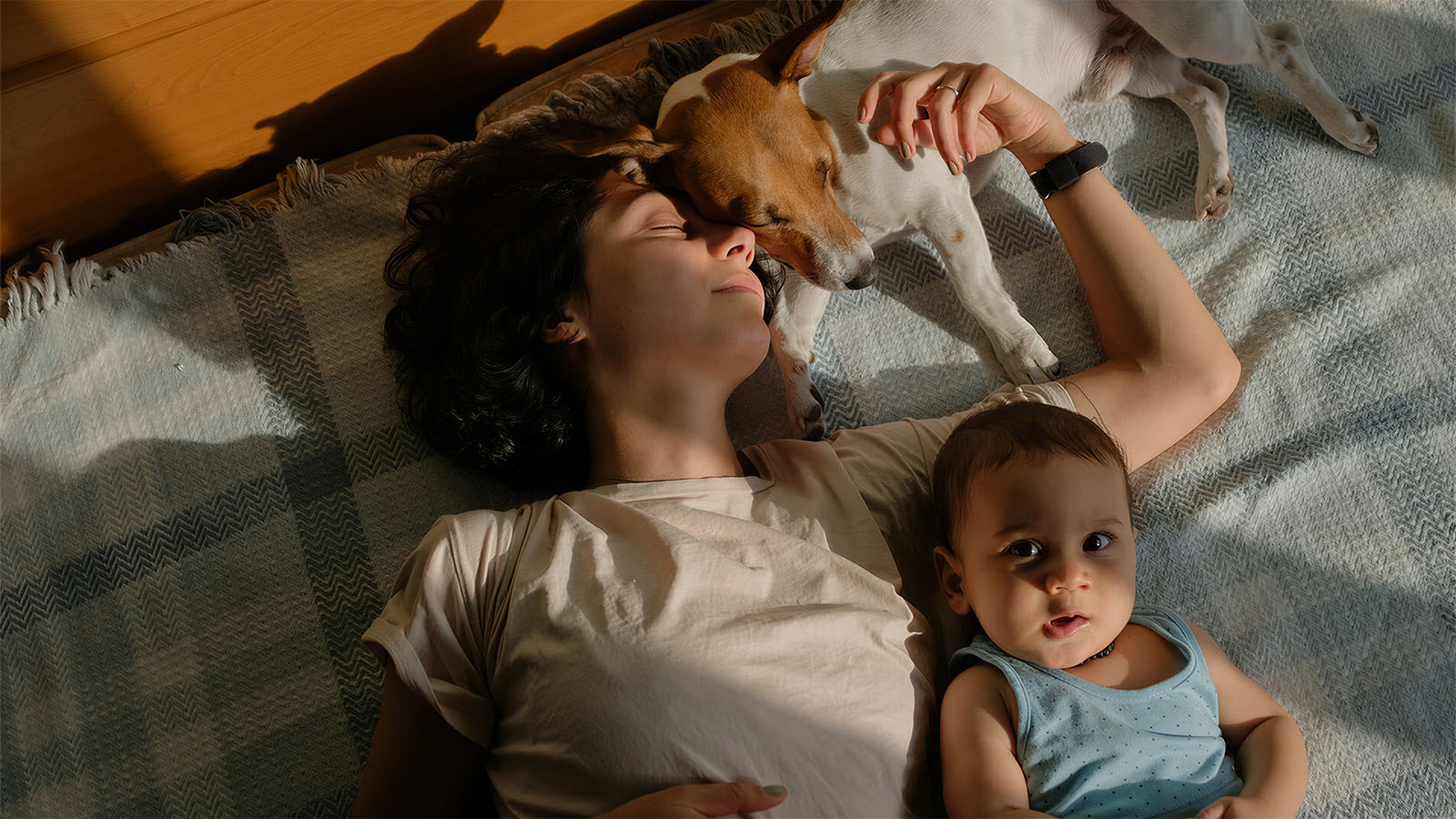 Woman and baby resting with a dog on a soft, skin-friendly dog bed, providing a safe and healthy space for pets and family.