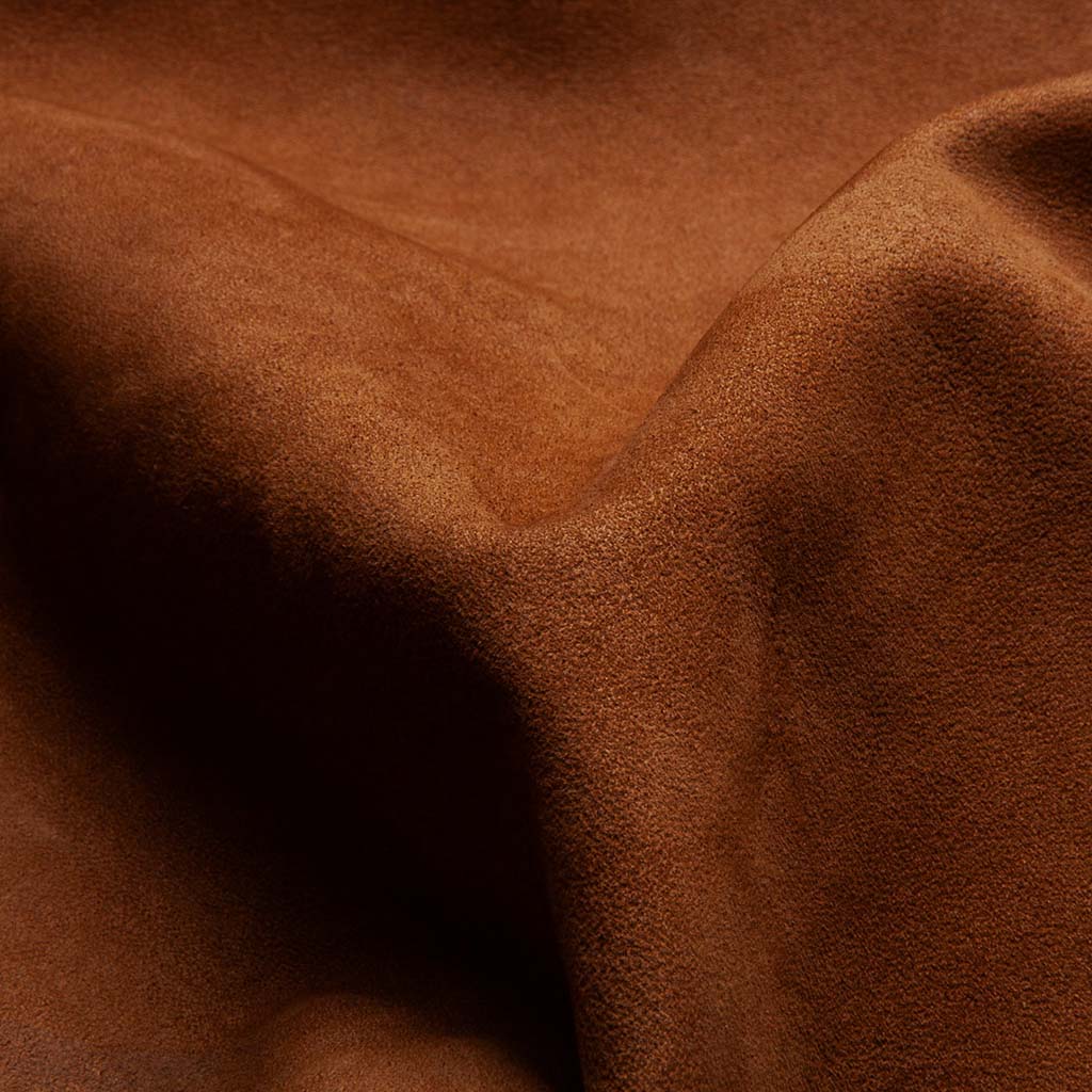 Macro close-up of full-grain cowhide leather surface showing natural texture, subtle grain variation, and soft warm tone used in Tailooo leather dog collars.