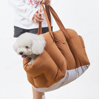 A woman carrying the portable dog car seat as a shoulder bag, with a cute puppy relaxed inside, walking along a scenic coastal path, highlighting its versatility.