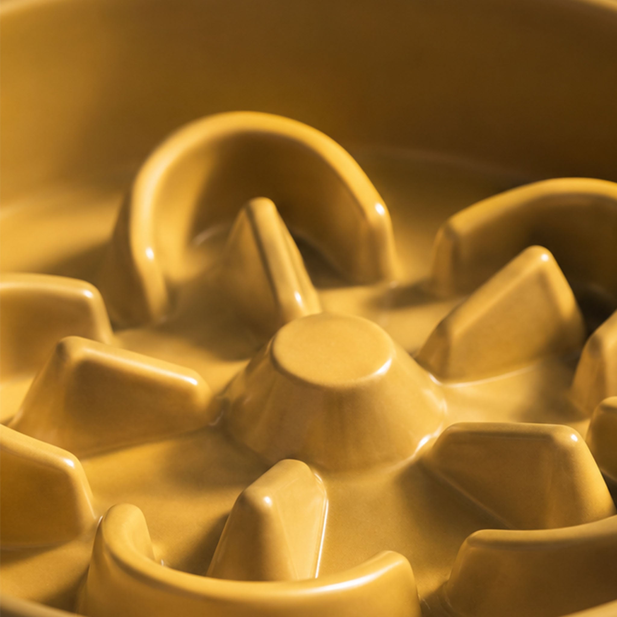 Macro close-up of yellow ceramic slow feeder dog bowl interior ridges, showcasing the smooth under-glaze finish and durable ceramic construction.